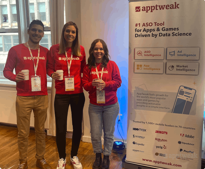 Three employees of AppTweak posing with an AppTweak banner.